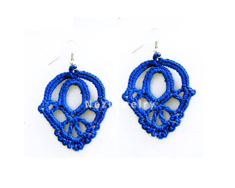 May include: A pair of blue crocheted earrings with a delicate, intricate design. The earrings are made with a fine thread and have a dangling, teardrop shape.
