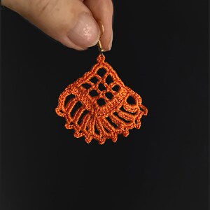 Puede incluir: Pendiente de ganchillo naranja con un delicado dise&ntilde;o floral y un gancho dorado.