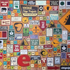 May include: A wall covered in vintage-style metal signs with various warnings, instructions, and humorous messages. The signs are in different shapes, sizes, and colors, with some featuring illustrations. The signs are arranged in a random pattern, creating a visually interesting and eclectic display.