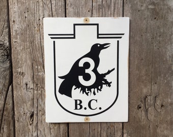 May include: Black and white sign with a crow silhouette holding the number 3 in its talons. The sign also says "B.C."