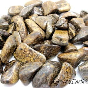 May include: A pile of tumbled brown and gold tiger iron stones. The stones are smooth and polished, with a variety of shapes and sizes.