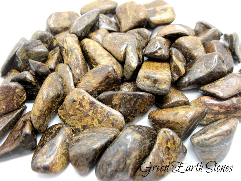 May include: A pile of tumbled brown and gold tiger iron stones. The stones are smooth and polished, with a variety of shapes and sizes.