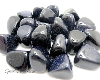 May include: A collection of tumbled blue sandstone stones. The stones are smooth and polished, with a deep blue color and a sparkly finish.