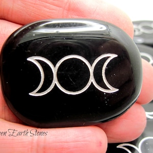 以下が含まれることがあります： 銀でエッチングされたトリプルムーンシンボルが付いた黒い黒曜石のパームストーン。Green Earth Stonesが石の下に印刷されています。