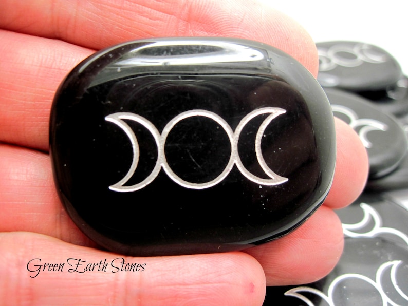 以下が含まれることがあります： 銀でエッチングされたトリプルムーンシンボルが付いた黒い黒曜石のパームストーン。Green Earth Stonesが石の下に印刷されています。