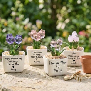 May include: A white ceramic mug with a black handle and the text "But First, Coffee" in a black, handwritten-style font. The mug is on a white surface.