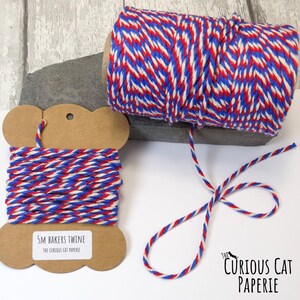 May include: Red, white, and blue baker's twine on a spool and a card. The twine is twisted together in a striped pattern. The card reads "5M Bakers Twine" and "The Curious Cat Paperie."