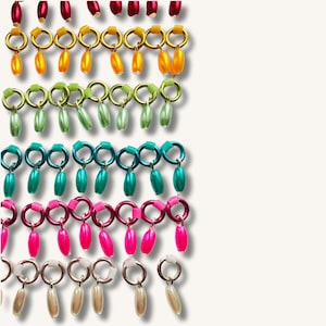 May include: A selection of colourful earrings in various designs. The earrings feature gold, silver, and coloured hoops with dangling beads in shades of red, yellow, green, teal, pink, and white. The earrings are arranged in a neat, organised display.