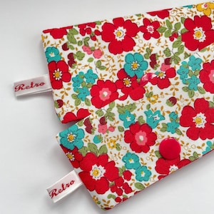 May include: A pair of red and white floral fabric pouches with a pink button on one pouch and the word "Retro" printed on a white label on each pouch.