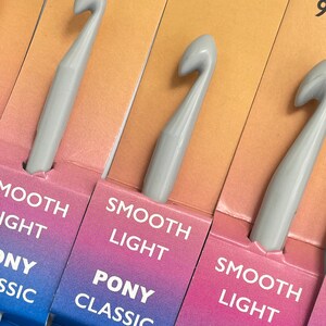 May include: A set of four gray crochet hooks with the text "Smooth Light Pony Classic" on the packaging. The hooks are labeled with sizes 8 mm, 9 mm, 10 mm, and 12 mm.