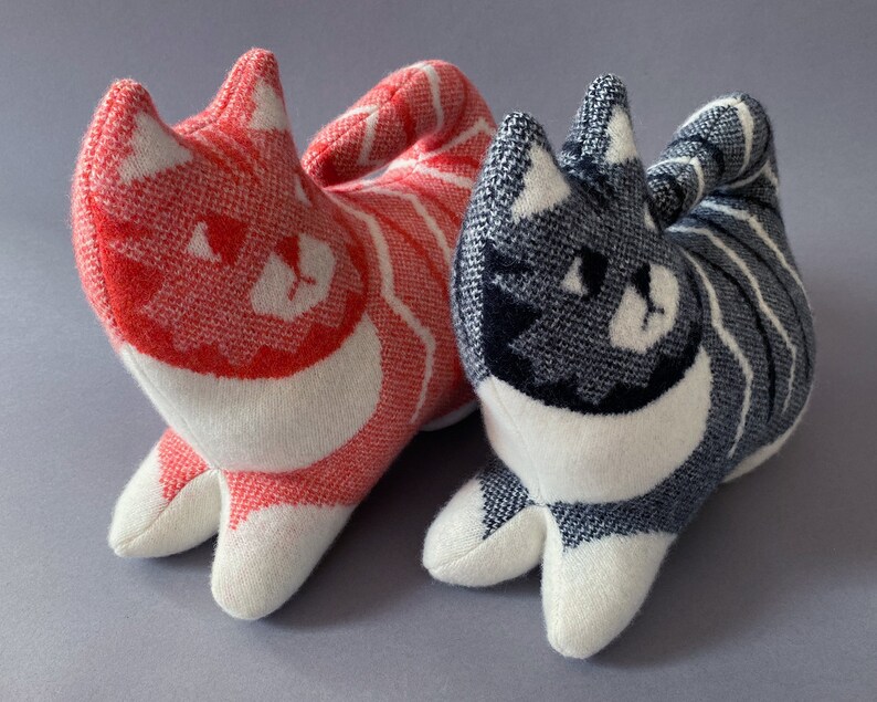 May include: Two plush cat toys, one red and white striped and the other gray and white striped. Both have white faces with black eyes and a black nose.