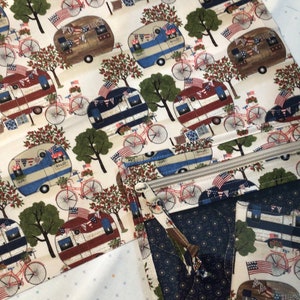 May include: Fabric with a repeating pattern of vintage camper trailers, bicycles, trees, and American flags in red, white, and blue. The fabric is used to create a zippered pouch and other items.