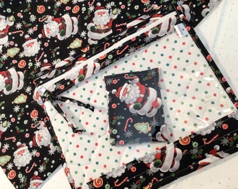 May include: A Christmas-themed quilted fabric item with a black background featuring Santa Claus, candy canes, and snowflakes. The item has a white zipper and a clear pocket, with a smaller matching pouch inside. The interior fabric has a white background with red and green polka dots.