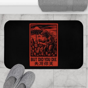 May include: Black bath mat with a red graphic of a Godzilla-like monster standing in front of a cityscape with the text "BUT DID YOU DIE" and "末 亦 你 天" in red.