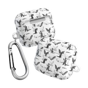 May include: White AirPod cases with a black and gray dinosaur pattern. The cases are shown with a silver carabiner clip. The cases have a smooth, glossy finish and are designed to protect the AirPods.