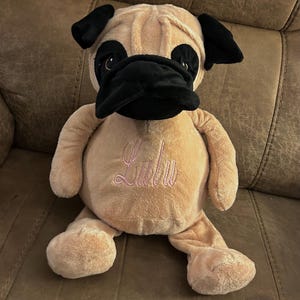 May include: A plush tan and black pug dog toy with pink embroidered text that says "Lulu".
