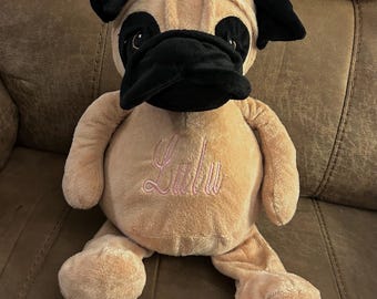 May include: A plush tan and black pug dog toy with pink embroidered text that says "Lulu".