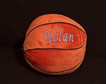 May include: A plush orange and black basketball with the name "Nolan" embroidered on it in blue thread.