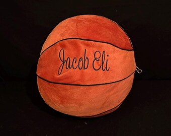 May include: A plush orange basketball with black stitching and the name "Jacob Eli" embroidered on it.