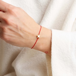 May include: A red string bracelet with a gold star charm.