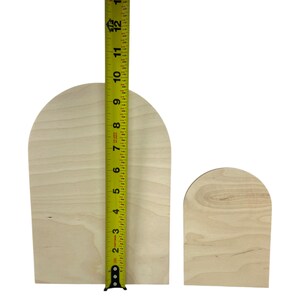 Puede incluir: Dos placas de madera clara sin terminar en forma de arco con veta visible. Una cinta m&eacute;trica amarilla est&aacute; colocada verticalmente contra la placa m&aacute;s grande, mostrando una altura de aproximadamente 30,5 cm desde la base hasta la curva superior.