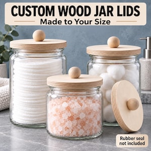 May include: Three clear glass jars with light-colored wooden lids featuring spherical knobs. The jars contain white cotton rounds, white cotton balls, and pink bath salts. Text reads: CUSTOM WOOD JAR LIDS Made to Your Size and Rubber seal not included.