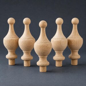 May include: Five unfinished light brown wooden finials arranged in a row. Each finial features a spherical top, a tapered neck, a rounded bulbous body, and a cylindrical base designed for mounting, showcasing a natural wood grain texture.