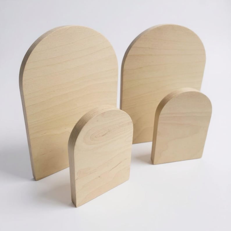 Puede incluir: Un conjunto de cuatro placas de madera de color claro, cada una con un dise&ntilde;o de parte superior arqueada y lisa. La colecci&oacute;n incluye dos tablas arqueadas m&aacute;s grandes y altas, y dos tablas arqueadas m&aacute;s peque&ntilde;as y cortas, con veta natural.