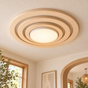 May include: A circular flush mount ceiling light fixture featuring concentric rings made of light-toned wood. The center of the fixture contains a frosted white glass diffuser that emits a soft, warm glow, creating a layered appearance.