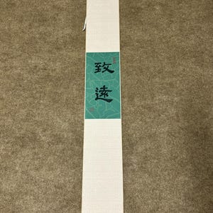 Peut inclure: Un rouleau blanc avec une calligraphie noire sur fond vert. La calligraphie dit "致敬".