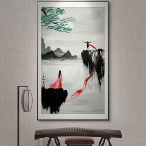 May include: A black and white ink painting of two figures in red robes standing on cliffs overlooking a misty landscape. The painting is framed and hanging on a wall.