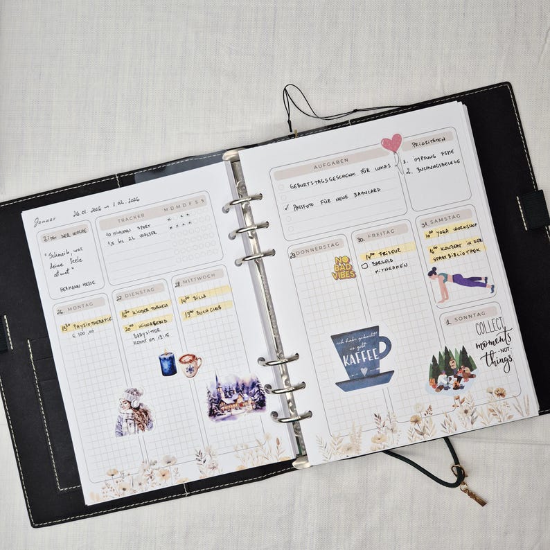 May include: Open black planner with a weekly layout. The pages are filled with handwritten notes, stickers, and decorative elements. The planner includes sections for tasks, trackers, and daily entries. The text "COLLECT moments not things" is visible.