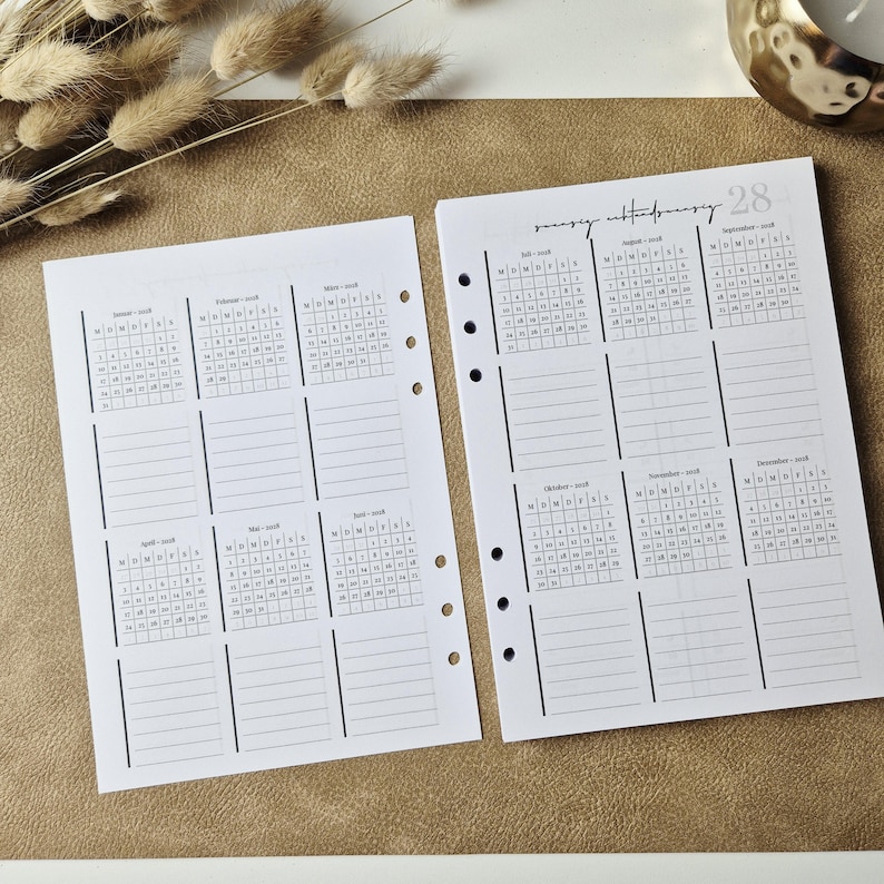 May include: Two white planner pages with black ink, featuring a 2018 calendar layout. Each page contains six monthly grids with corresponding lined note sections. The pages have pre-punched holes along the inner edges for binder insertion.