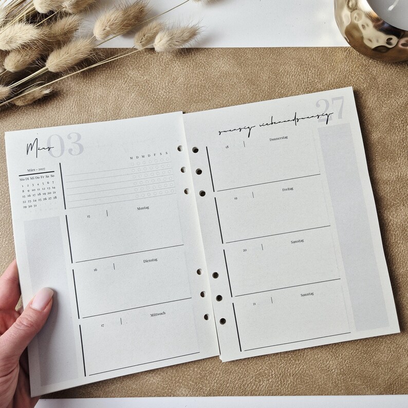 May include: An open planner with white pages featuring black text and lines. The left page shows a monthly calendar for March, a weekly schedule, and a list of checkboxes. The right page displays daily sections for Thursday through Sunday.