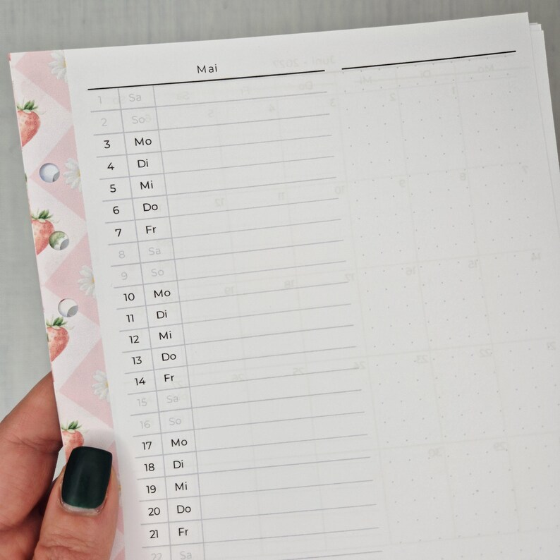May include: A partially visible planner page with the month of May. The left side has a pink border with strawberry and daisy patterns. The page is divided into days of the week with lines for notes. The word "Mai" is at the top.