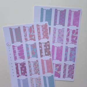 Può includere: Due fogli di adesivi per planner con linguette decorate in rosa, blu e marrone. Le linguette presentano disegni floreali, geometrici e a pois. Il testo "4 y t e p i a n n e r" è stampato su un foglio.