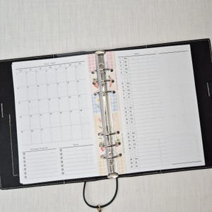 May include: Open black leather binder with a calendar and daily planner pages. The calendar shows the month of March 2021. The planner pages have a floral design and a to-do list.