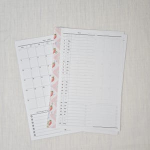 May include: Two white paper calendar pages with the month of May 2027 printed on them. One page is a calendar view, and the other is a planner view. A pink and white strawberry-patterned border is on the left side.