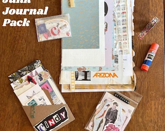May include: A collection of junk journal supplies, including patterned papers, stickers, and ephemera. The image features a variety of decorative elements, such as washi tape, a glue stick, and a paper clip. The text "Standard Junk Journal Pack" is visible.