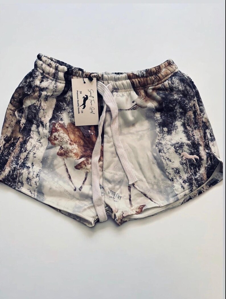 Puede incluir: Shorts blancos, marrones y grises con estampado y cord&oacute;n blanco. Los pantalones cortos tienen una etiqueta que dice "Salt River Girl" y "Premium Country Goods".