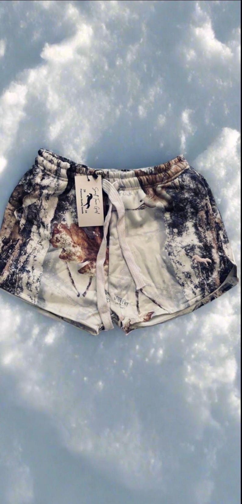 Puede incluir: Shorts de algod&oacute;n blanco con estampado de bosque que incluye &aacute;rboles, nieve y ciervos. Los shorts tienen cintura con cord&oacute;n y una etiqueta que dice "Small Town Girl" con un logotipo de caballo.