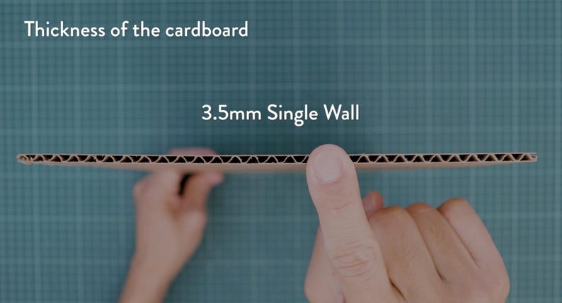 May include: A close-up of a piece of corrugated cardboard, held between two hands. The text "Thickness of the cardboard" and "3.5mm Single Wall" are visible. The cardboard has a brown, ridged interior.