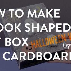 May include: A handmade book-shaped gift box made from cardboard, decorated with Halloween-themed elements. The box features a gray background with a spiderweb, ghost, and jack-o'-lantern design. The text reads "HOW TO MAKE A BOOK SHAPED GIFT BOX from CARDBOARD".