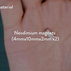 May include: A close-up of a hand holding two small, rectangular neodymium magnets. The magnets are silver and measure 4mm x 10mm x 2mm each. Text in the image reads "Neodimium magnets (4mmx10mmx2mm x2)" and "Additional material".
