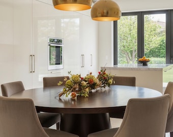 Centro de mesa italiano de madera flotante con tallos de granada y peonías para comedor de estilo rústico.