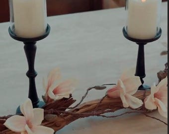 Centro de mesa de madera flotante: magnolia, candelabros negros, velas sin llama