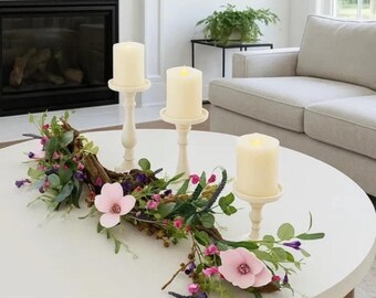 Centro de mesa con flores silvestres, eucalipto y magnolia, con portavelas de madera flotante.