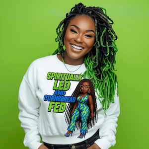 Puede incluir: Sudadera blanca con un estampado gráfico de una mujer de dibujos animados con cabello verde y el texto "Spiritually Led and Cornbread Fed".