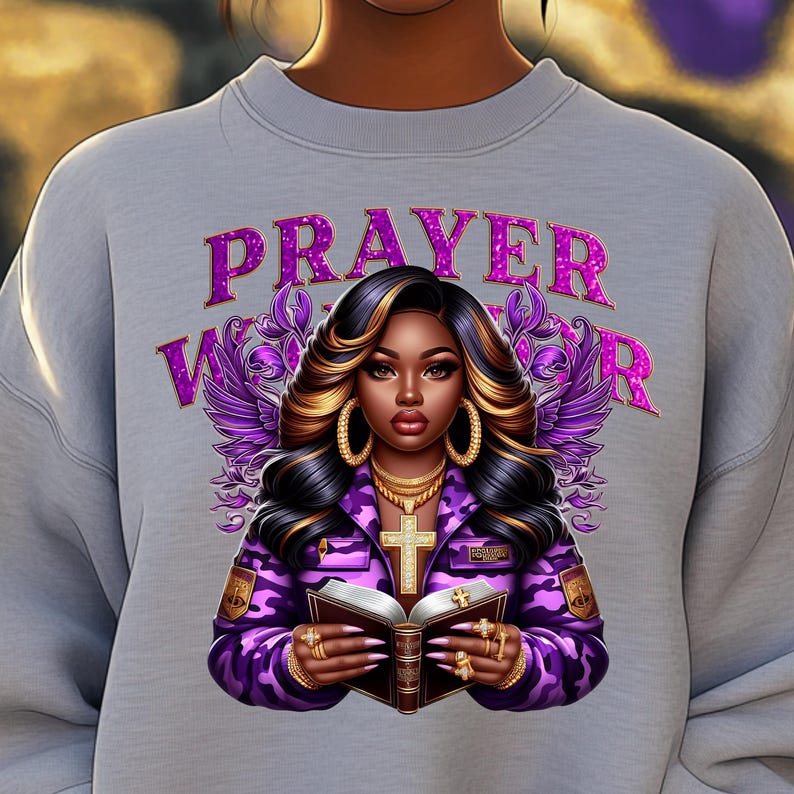 May include: A gray sweatshirt with a purple glitter design featuring a woman with long black and blonde hair holding a book and a cross. The text "PRAYER WARRIOR" is written in purple glitter.