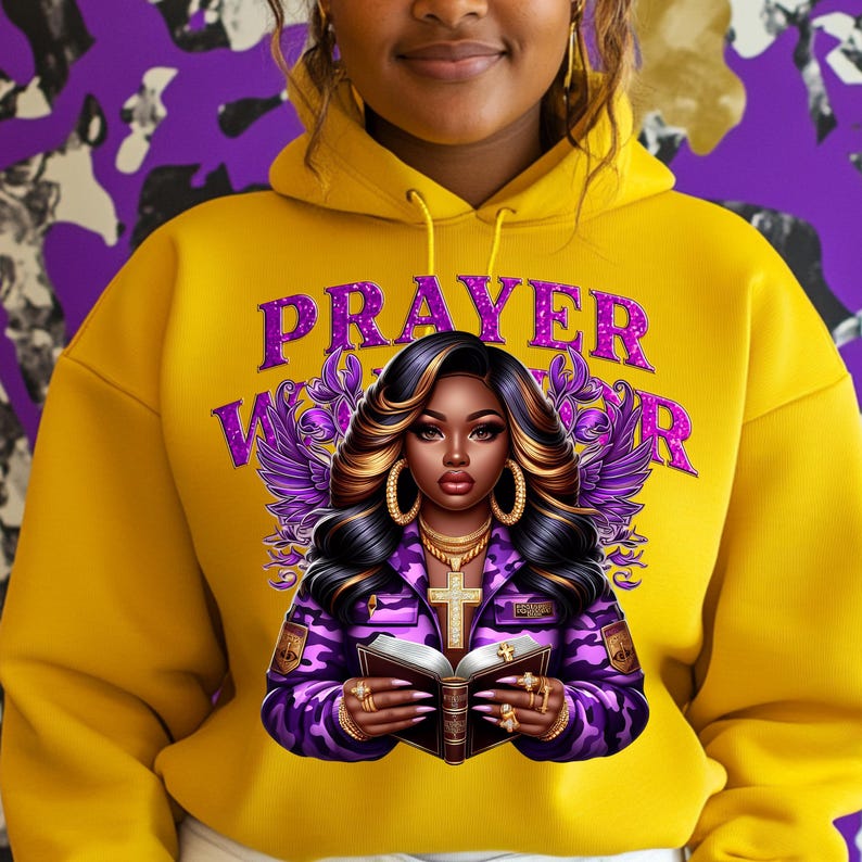 May include: A yellow hoodie with a purple graphic of a woman with long hair holding a book. The text "PRAYER WARRIOR" is written in purple glitter letters.